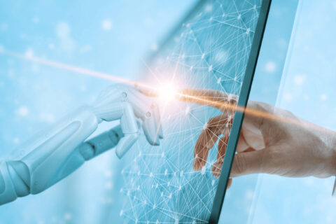 Auf diesem Bild sieht man, wie eine Roboterhand und die Hand eines Menschen sich berühren.